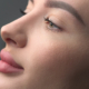 Close up side profile of a young woman with smooth skin and balanced facial features, focusing on the nose shape and nasal bridge.
