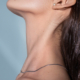 Close-up of a woman’s jawline and neck tilted upward, highlighting smooth skin, a defined jawline, and slender neckline with long straight hair tucked behind the ear.