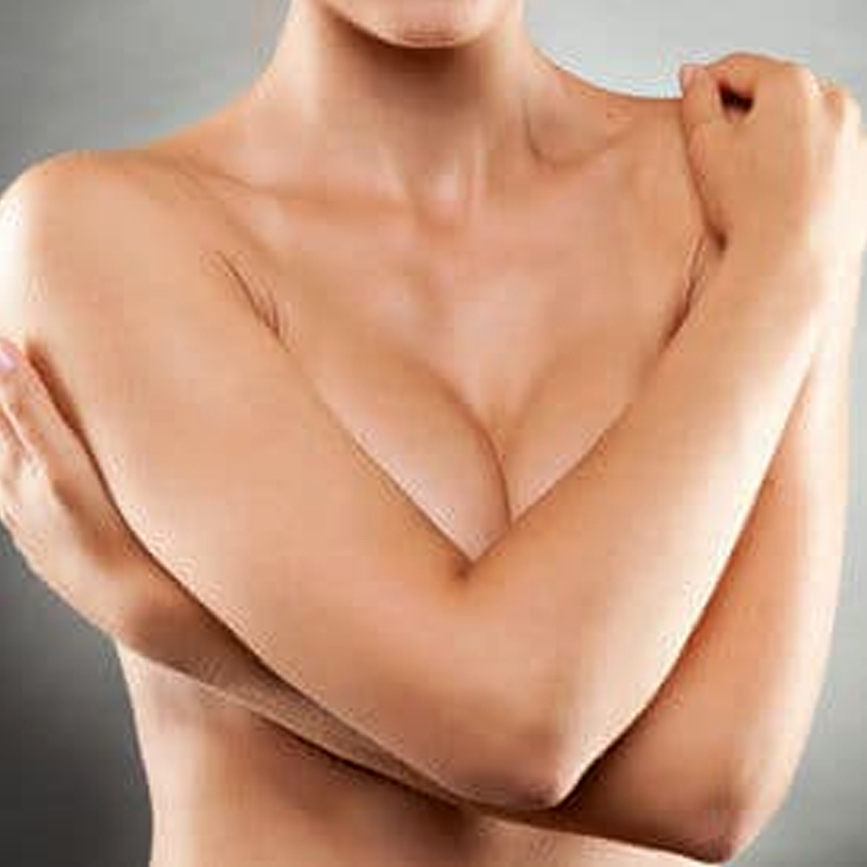 Close-up of a woman covering her chest with her arms, showing fuller breast shape after breast augmentation surgery