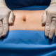 Surgeon evaluating abdominal contour before tummy tuck or mommy makeover surgery.