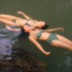 Women with natural-looking breast augmentation results enjoying an active lifestyle in the water.