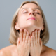 Woman gently touching her jawline and neck, representing combined facelift and neck lift surgery by Dr. Balikian.